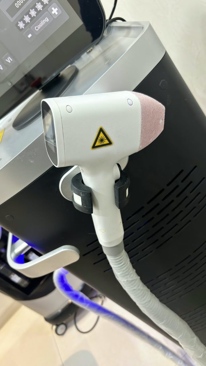 The laser handpiece with its cooling control on the console behind it.